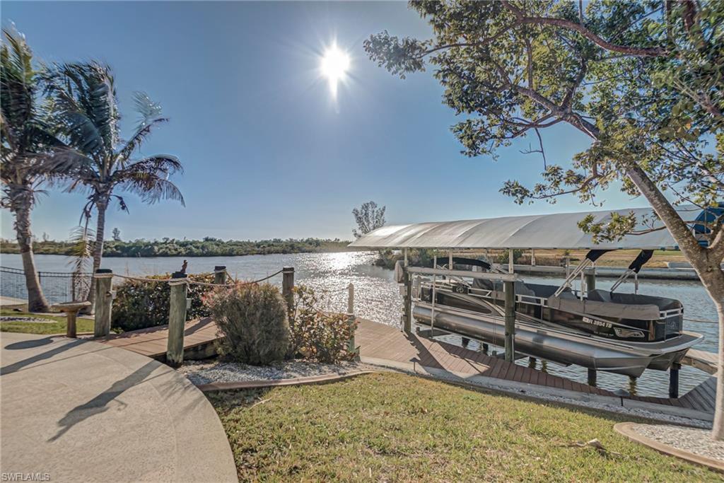 Image 4: Dock area featuring boat lift, a water view, and a yard