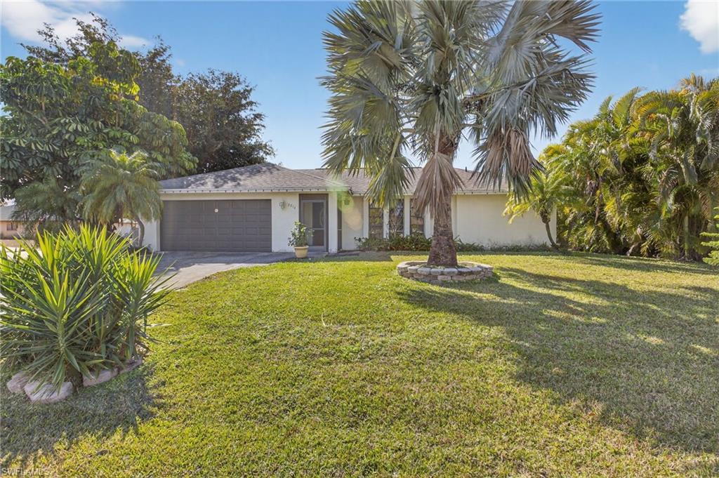 Image 2: Ranch-style house featuring stucco siding, a front lawn, an attached garage, and driveway