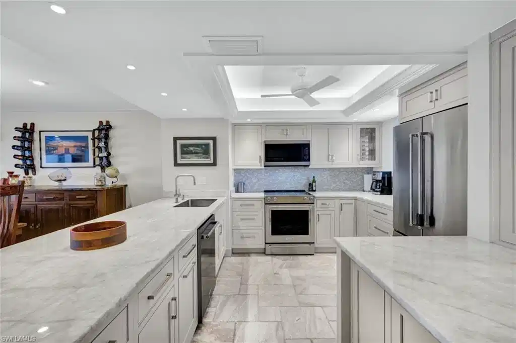 Image 1: Kitchen with stainless steel appliances, a raised ceiling, light stone counters, a ceiling fan, and recessed lighting