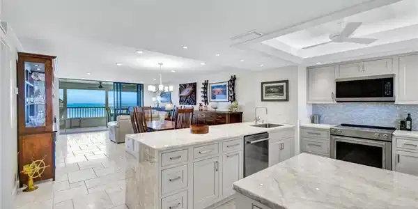 Image 2: Kitchen featuring light stone counters, a peninsula, a ceiling fan, stainless steel appliances, and a tray ceiling