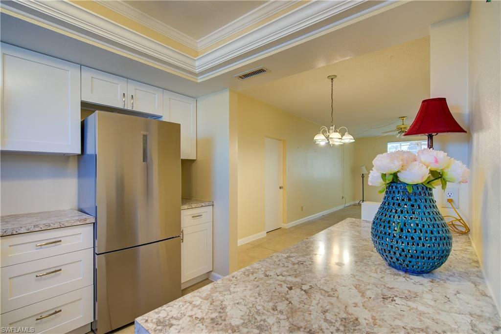 Image 2: Kitchen featuring freestanding refrigerator/freezer, white cabinetry, ornamental molding, and attractive laminate counters.