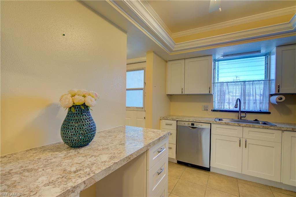 Image 3: Kitchen featuring dishwasher, white cabinetry, healthy amount of natural light, light countertops, and ornamental molding, ceiling fan