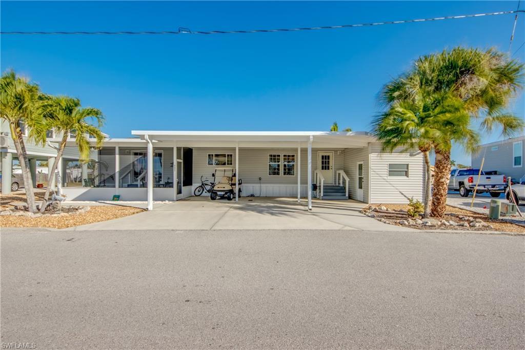 Image 2: View of front facade with an attached carport and concrete driveway
