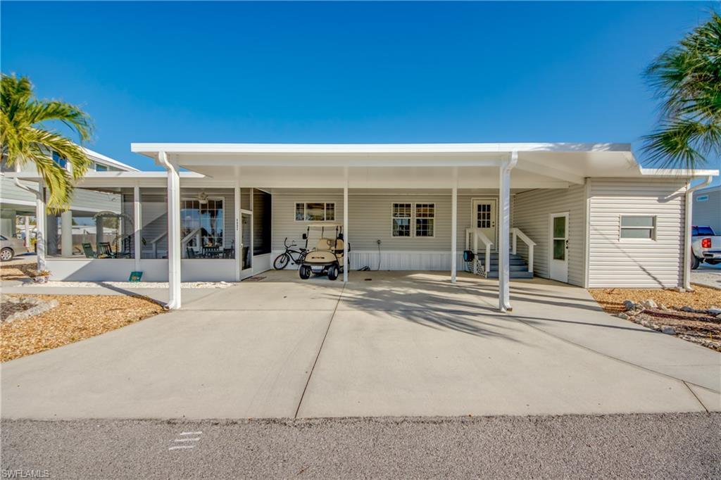 Image 3: Rear view of property featuring a carport, driveway, and entry steps
