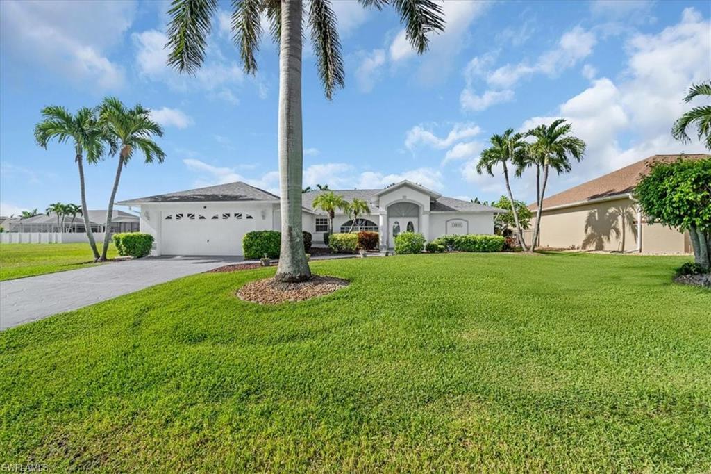 Image 2: View of front of property featuring an attached garage, driveway, a front lawn, and stucco siding