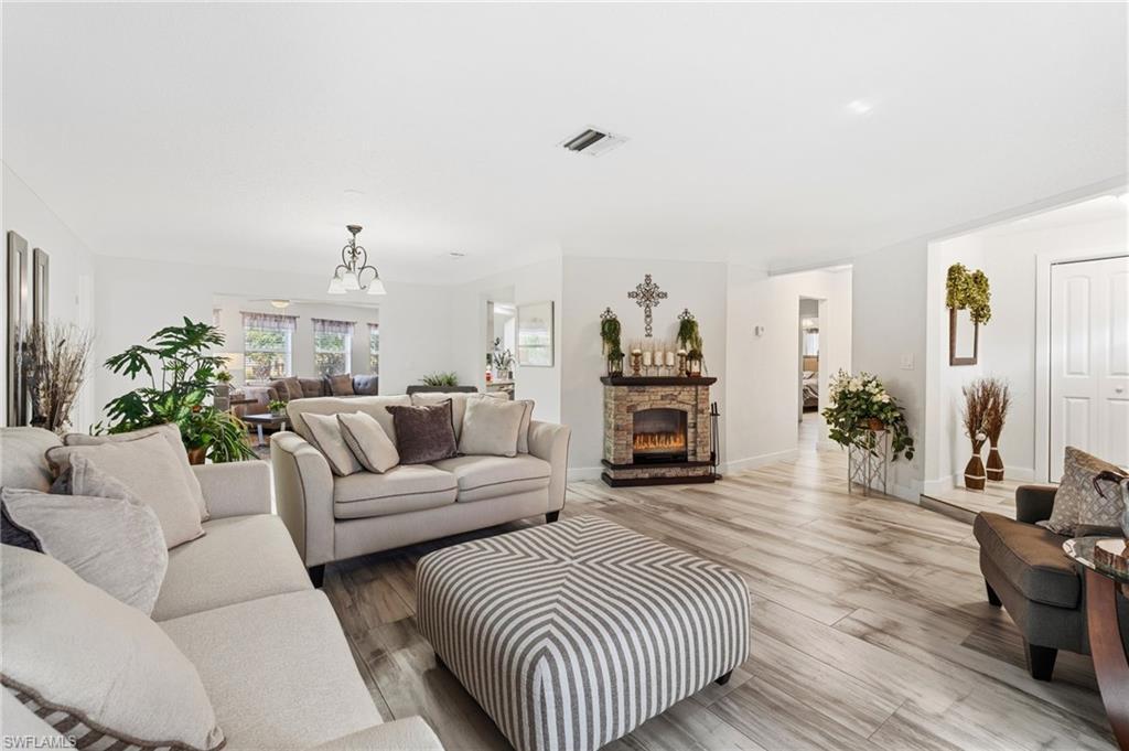 Image 3: Living room with wood finished floors, a fireplace, and a chandelier