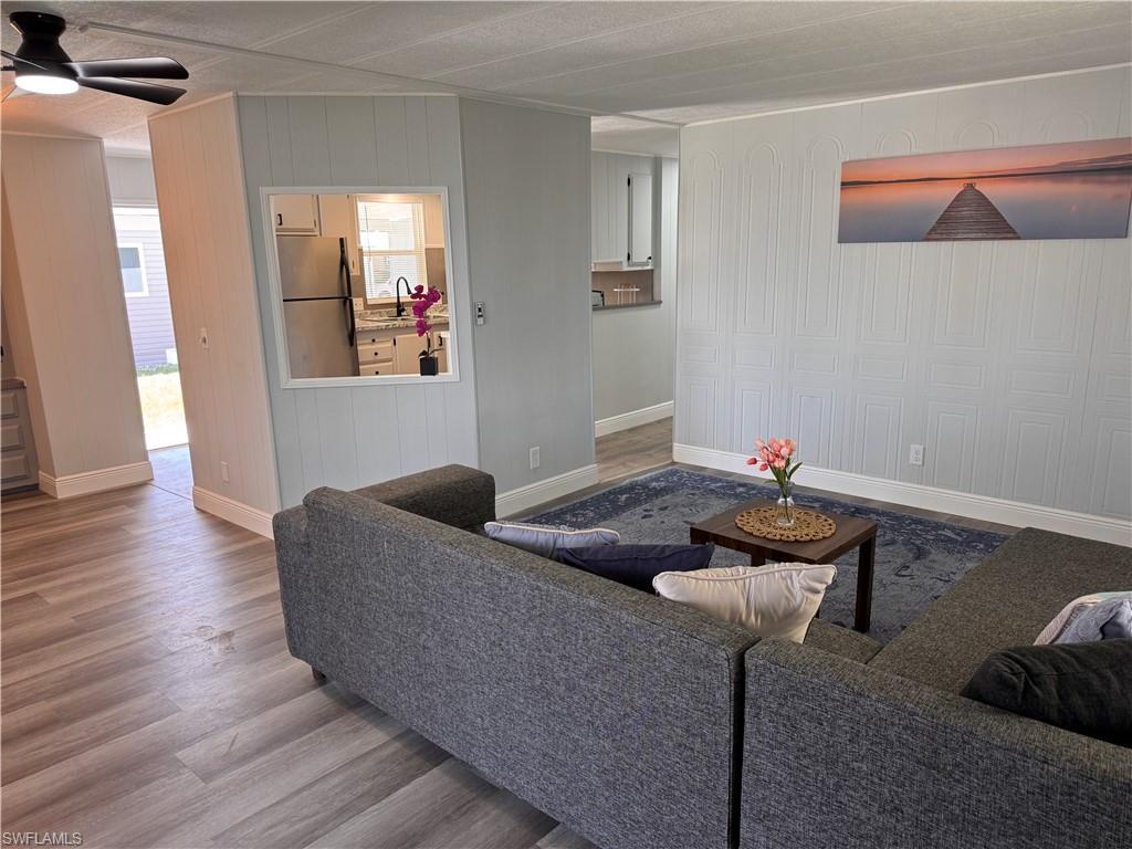 Image 3: Living room view of kitchen and dining.  Decorative accent wall, laminate flooring