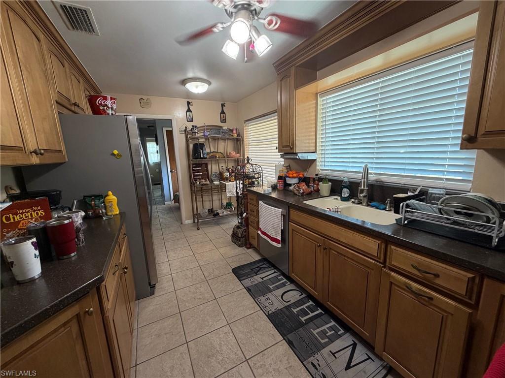 Image 3: Kitchen with a ceiling fan, Quarts countertops, stainless steel appliances, light tile patterned floors, and wood finish cabinets