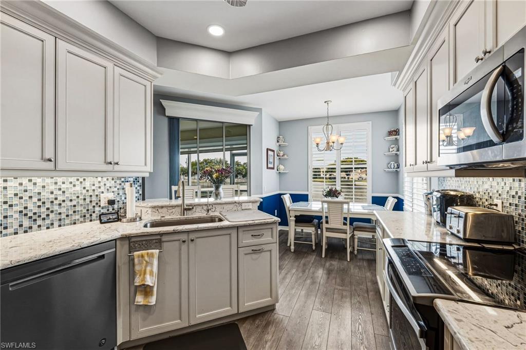 Image 3: A beautifully redesigned kitchen overlooking the tranquil lake, showcasing exquisite blue-veined granite countertops and matching backsplash, enhanced by ambient under-cabinet lighting, recessed illumination, and a suite of premium stainless steel appliances.