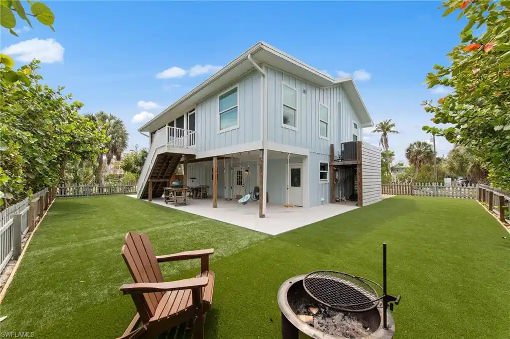 Image 1: Back of house featuring board and batten siding, a patio, a fenced backyard, a fire pit, and a balcony