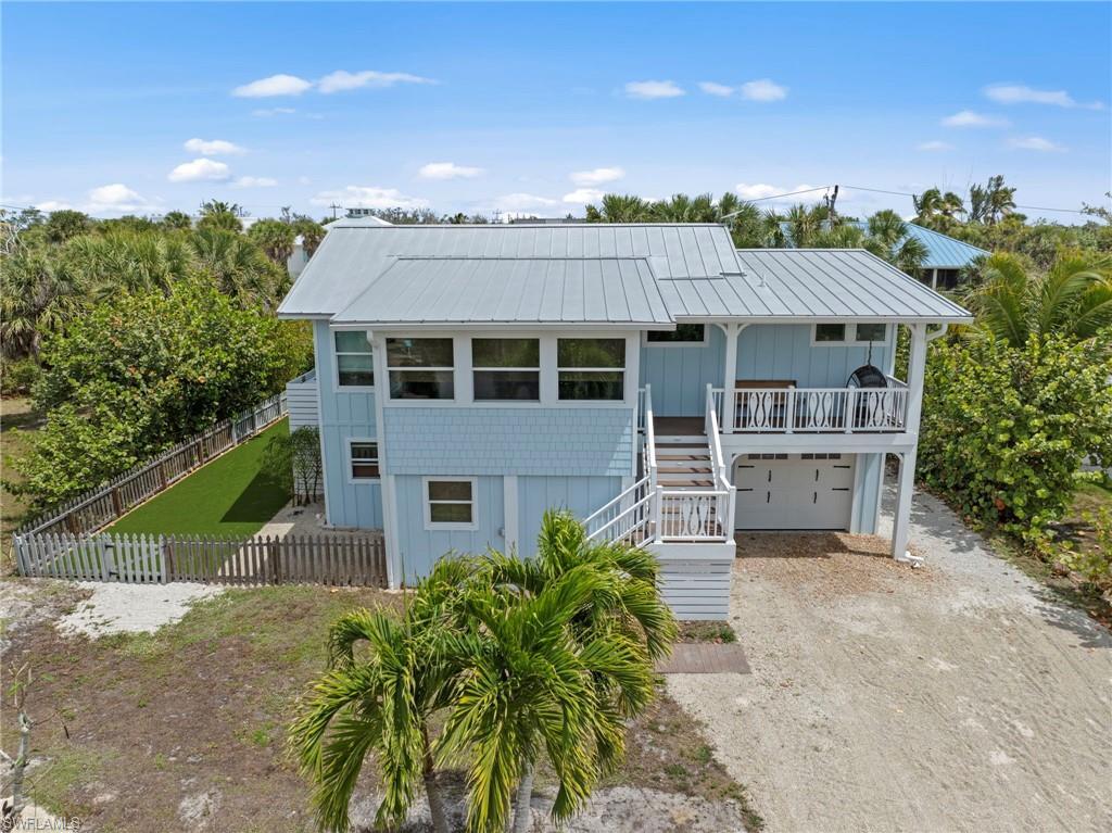 Image 3: Coastal home featuring driveway, an attached garage, a metal roof, and board and batten siding