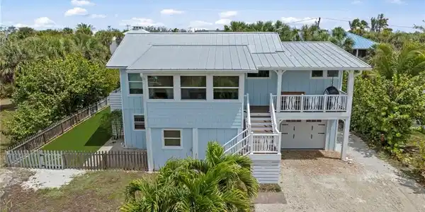 Image 3: Coastal home featuring driveway, an attached garage, a metal roof, and board and batten siding