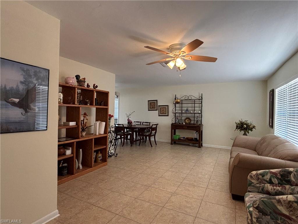 Image 3: The open-concept living area features neutral-toned walls, tiled flooring, and a ceiling fan with integrated lighting