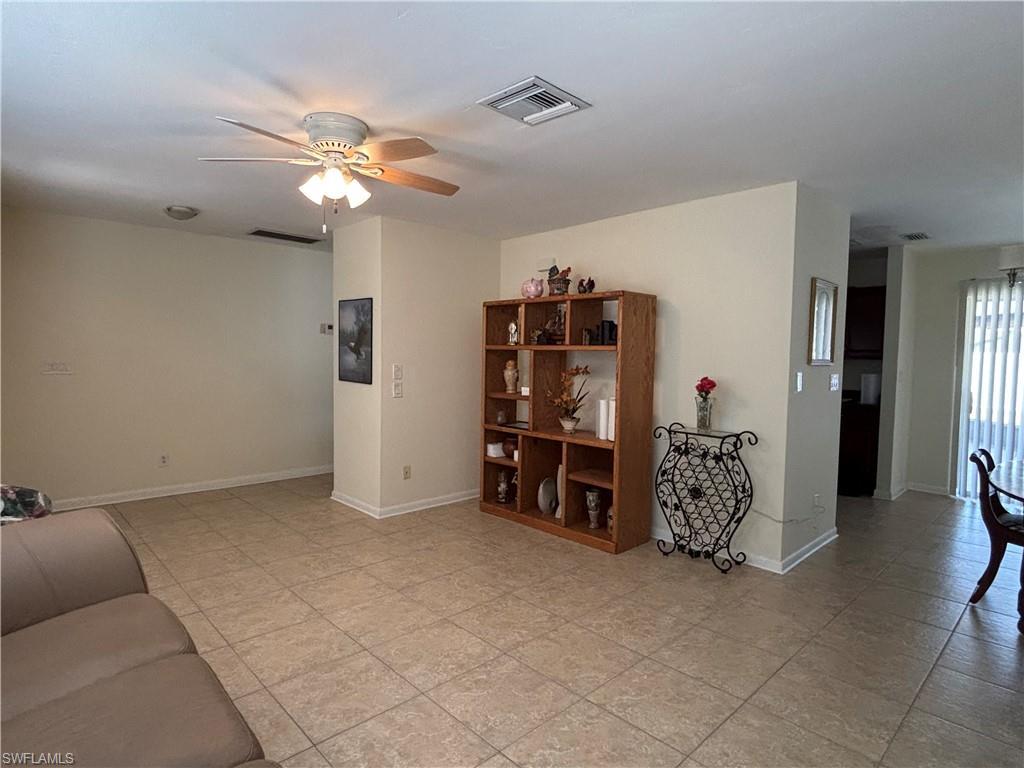 Image 4: This living area features neutral-toned walls, tile flooring, and a ceiling fan with integrated lighting