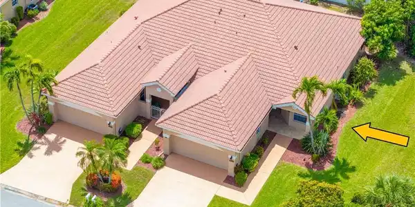 Image 2: The property features a terracotta tile roof, well-maintained lawn, multiple palm trees, and two separate driveways leading to garages