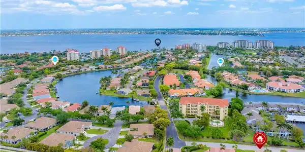 Image 3: Aerial view of the property's community, featuring a large body of water, residential properties with landscaping, and a distant coastline