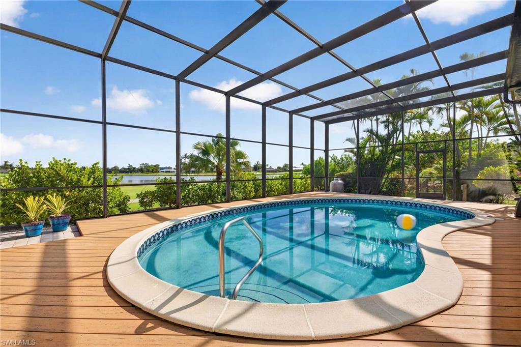 Image 3: Screened pool enclosure featuring a kidney-shaped pool with a textured perimeter, surrounded by a wood-finish deck