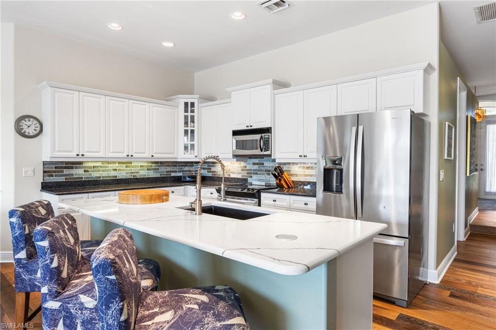 Image 4: This kitchen pulls out all the stops&mdash;custom white cabinetry, a subway tile backsplash with underlighting, sleek stainless steel appliances, quartz countertops with not one but two pop-up charging stations (because even your phone deserves luxury), all glowing under perfectly placed recessed lighting.