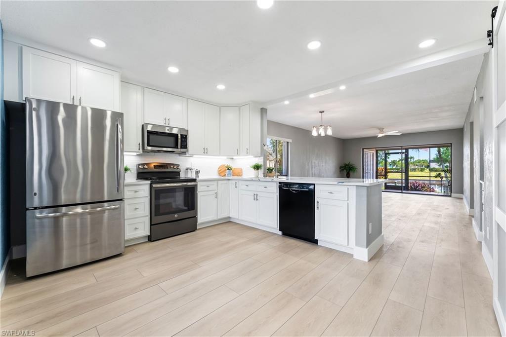 Image 3: Modern kitchen featuring white cabinetry, stainless steel appliances, and a central island with a dishwasher