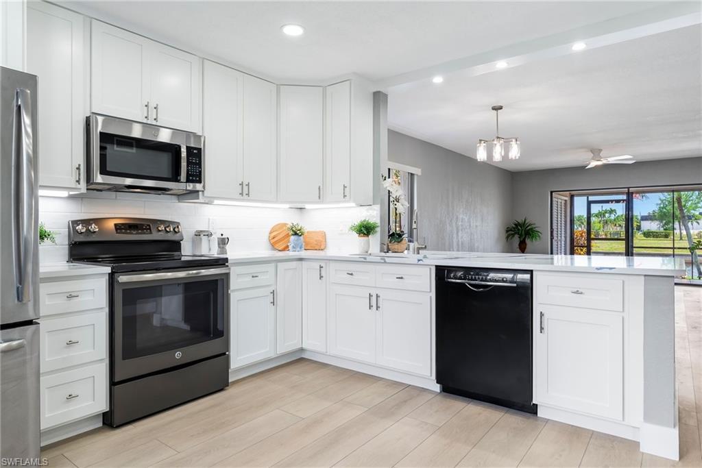 Image 4: Kitchen featuring white shaker cabinetry, stainless steel appliances, light-toned countertops, and wood-finish flooring
