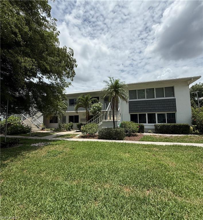 Image 2: Two-story stucco structure featuring a white exterior with a gray shingle accent band