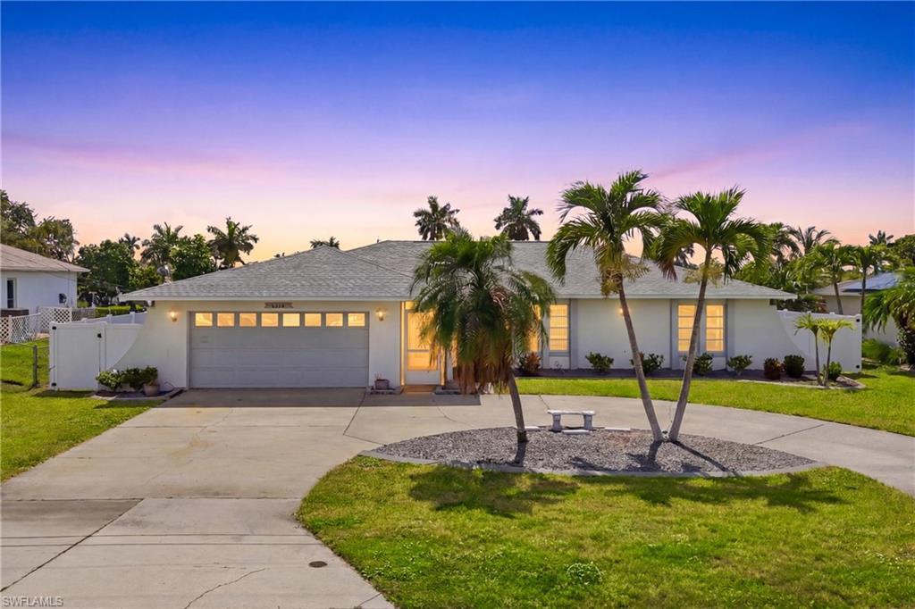 Image 2: This beautifully maintained Gulf-access residence offers a warm welcome with attractive landscaping, a spacious driveway, and timeless Florida charm.