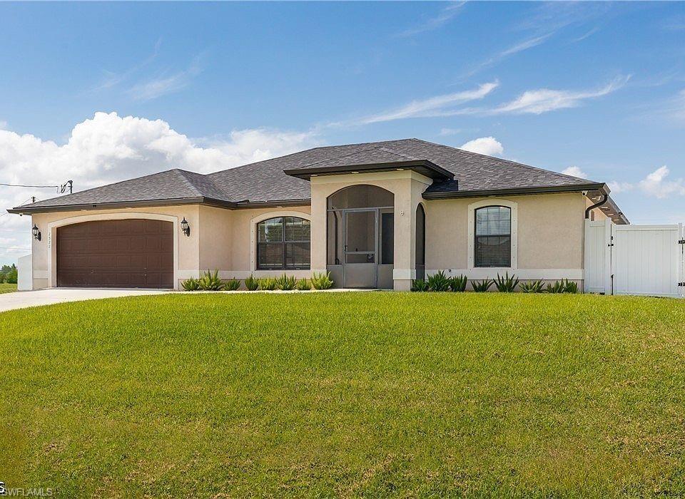 Image 2: Stucco exterior featuring a screened entry, arched windows, and a brown garage door