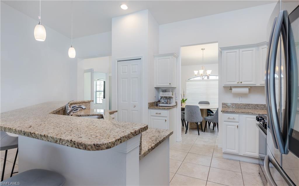 Image 4: Kitchen featuring granite countertops, white cabinetry, stainless steel appliances, pendant lighting, and tiled flooring