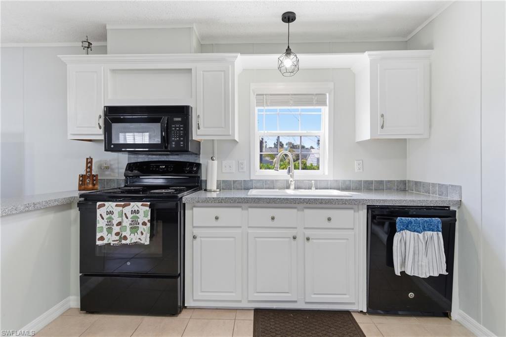 Image 1: Kitchen featuring white cabinetry, black appliances including a built-in microwave and dishwasher, a stainless steel sink, and gray countertops with a tiled backsplash