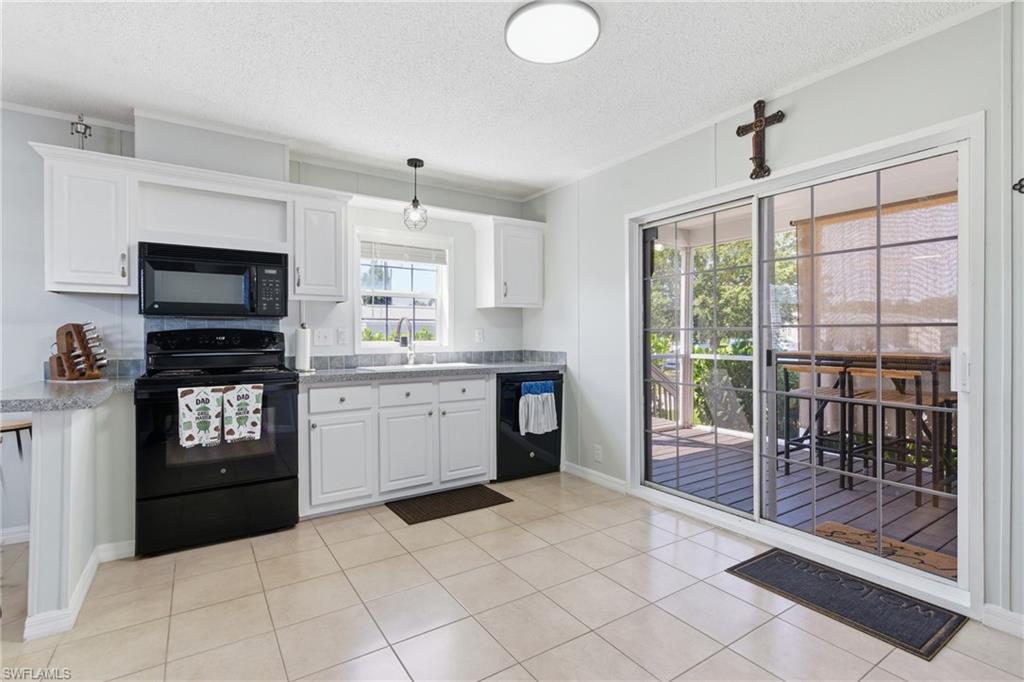Image 3: Kitchen featuring white cabinetry, grey speckled countertops, tile flooring, and sliding glass doors to the exterior