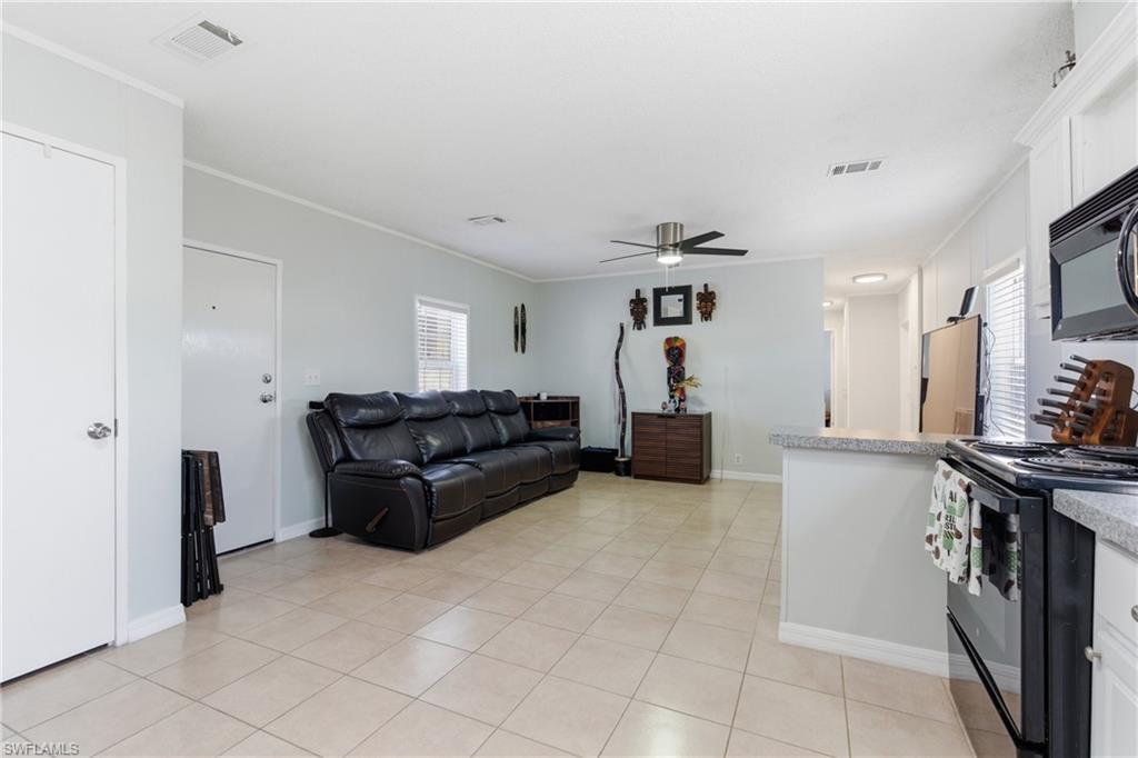 Image 4: Open-concept living space featuring neutral tile flooring, a ceiling fan, and light gray wall tones