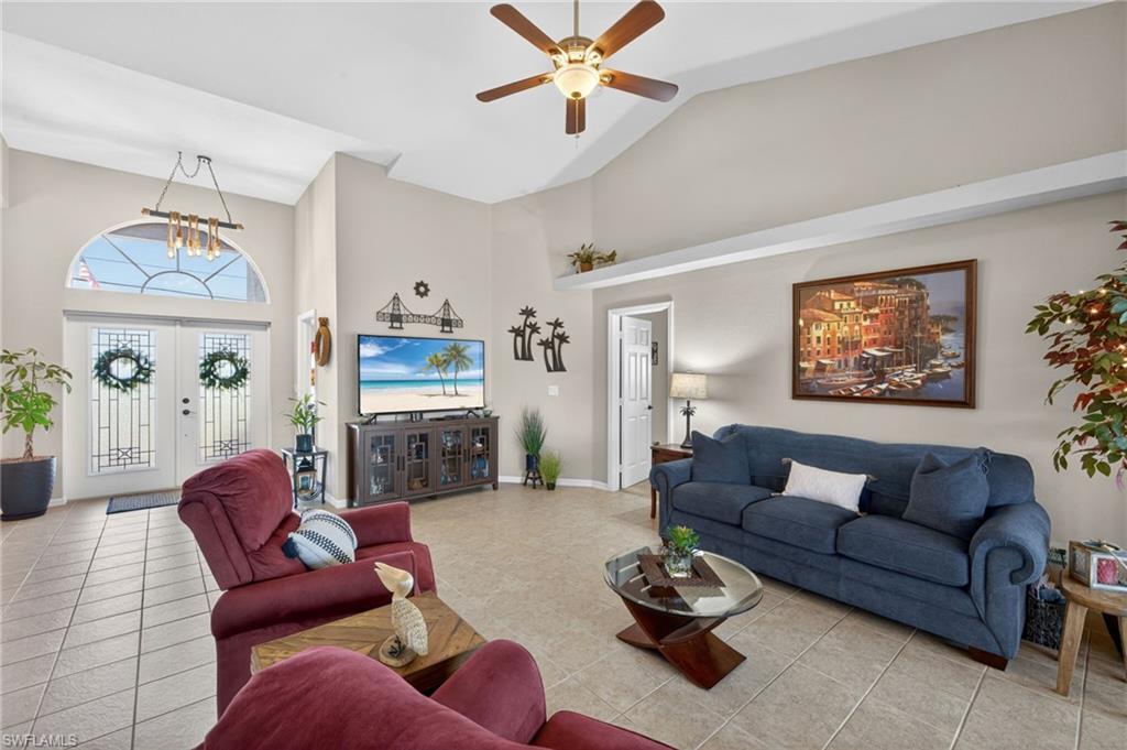 Image 4: Living area featuring vaulted ceilings with a ceiling fan, tile flooring, and double entry doors with an arched transom window