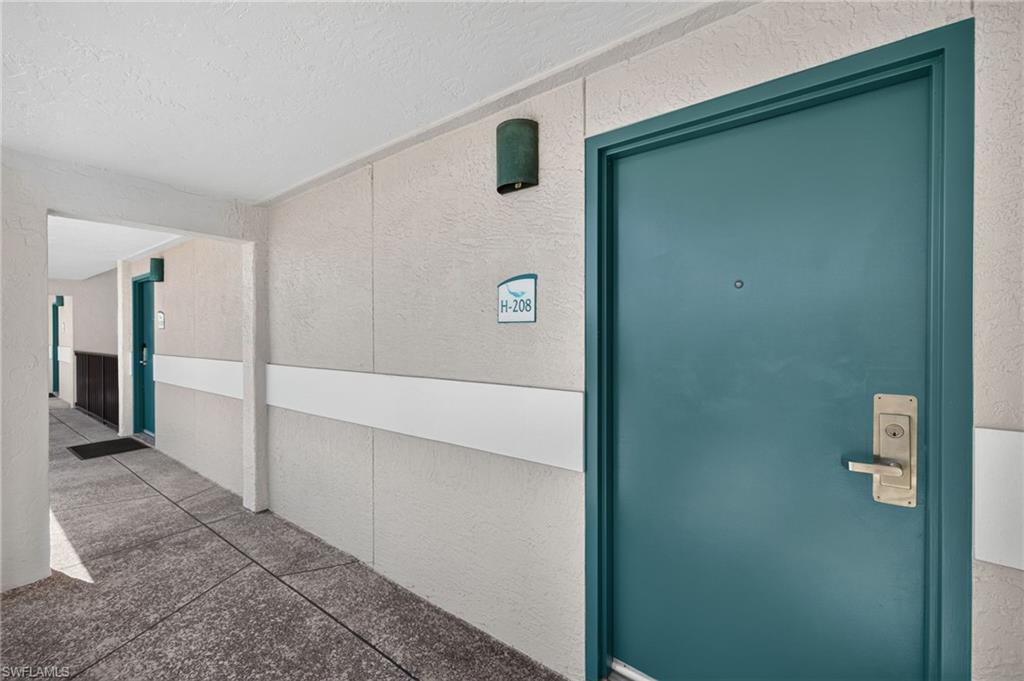 Image 2: Teal entry door with brushed brass hardware and peep hole