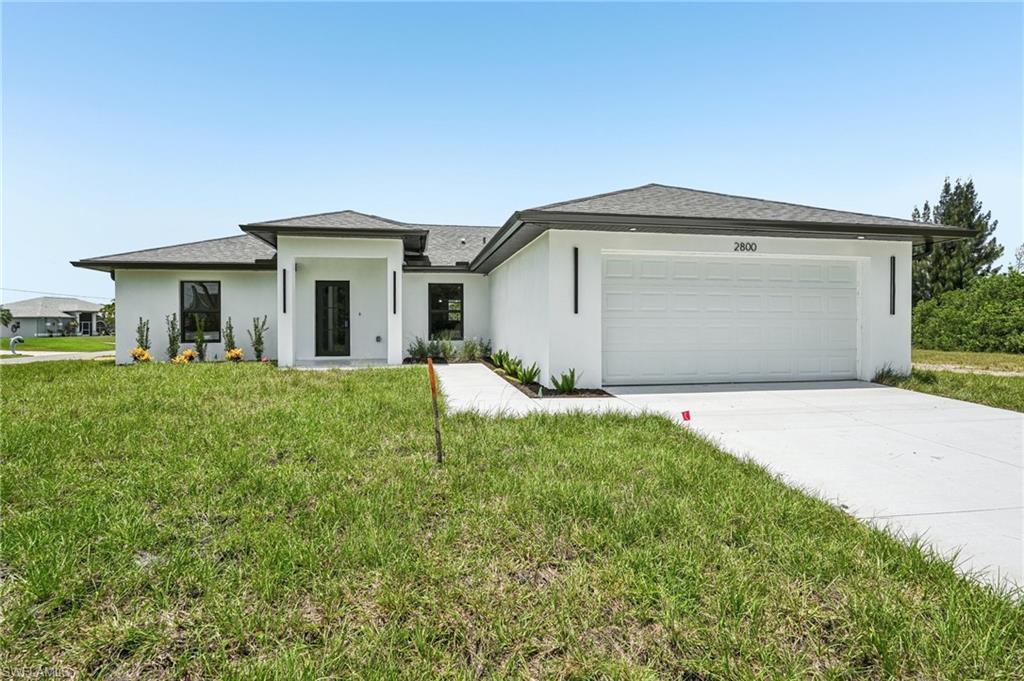 Image 1: Contemporary single-story exterior with a white stucco finish, dark framed windows, a covered entry, an attached garage, and a concrete driveway