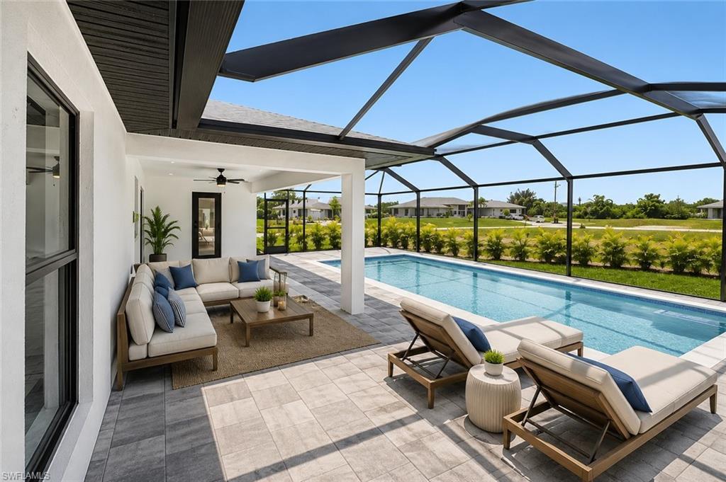 Image 3: Expansive screened-in lanai featuring a rectangular swimming pool, integrated covered patio, and textured paver flooring