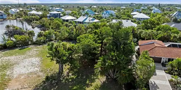 Image 2: Expansive residential lot featuring mature trees and a partial water perimeter