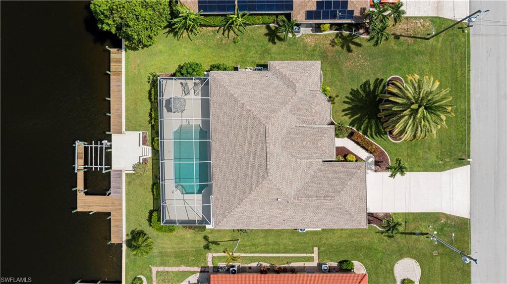 Image 2: Waterfront property featuring a screened-in swimming pool, private boat dock with lift, and concrete driveway