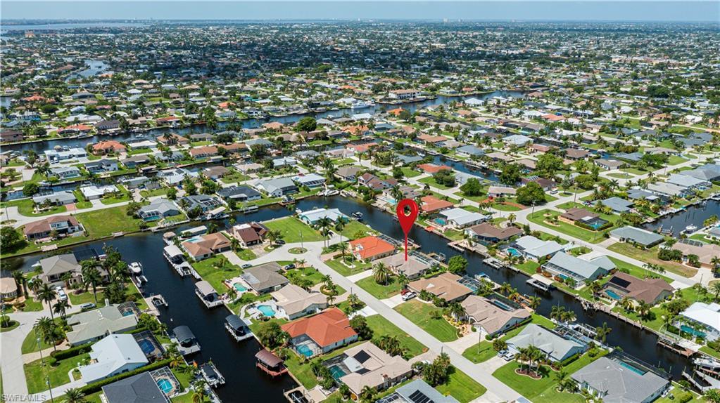 Image 4: Aerial perspective showcasing a canal-front property with a red tile roof, surrounded by a network of waterways and residential homes