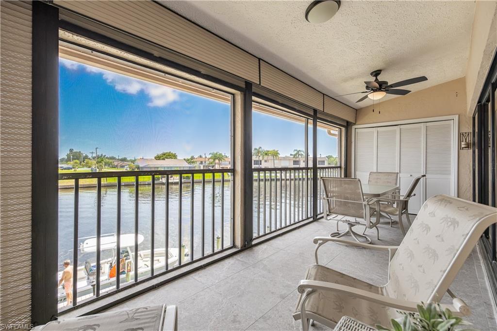 Image 2: Screened outdoor living area featuring a waterway, black iron railing, beige ceiling, ceiling fan, and sliding closet doors