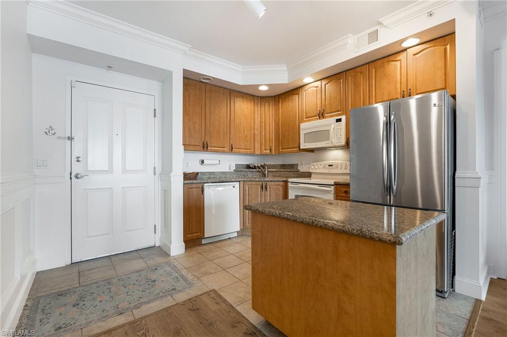 Image 4: Kitchen featuring crown molding, white appliances, a kitchen island, and light tile patterned floors