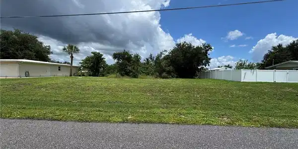 Image 4: Grassed lot with mature perimeter trees and a partial white privacy fence