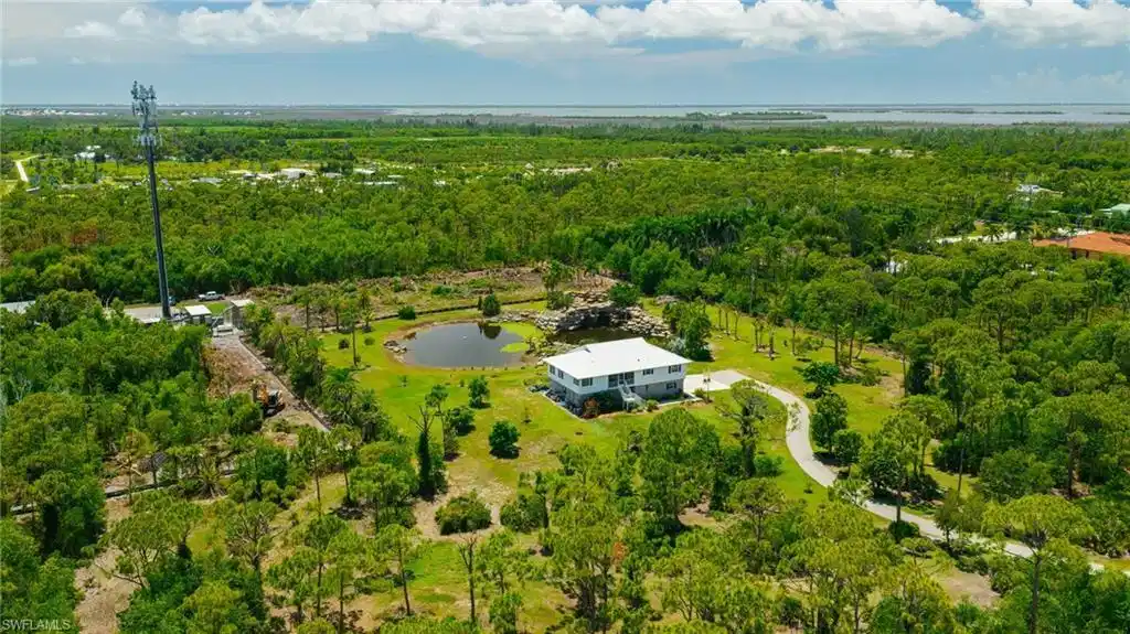 Image 1: Expansive natural landscaping with mature trees, private driveway, and a large pond feature