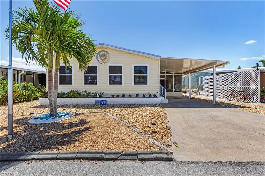Image 1: Manufactured / mobile home featuring an attached carport, a sunroom, and driveway