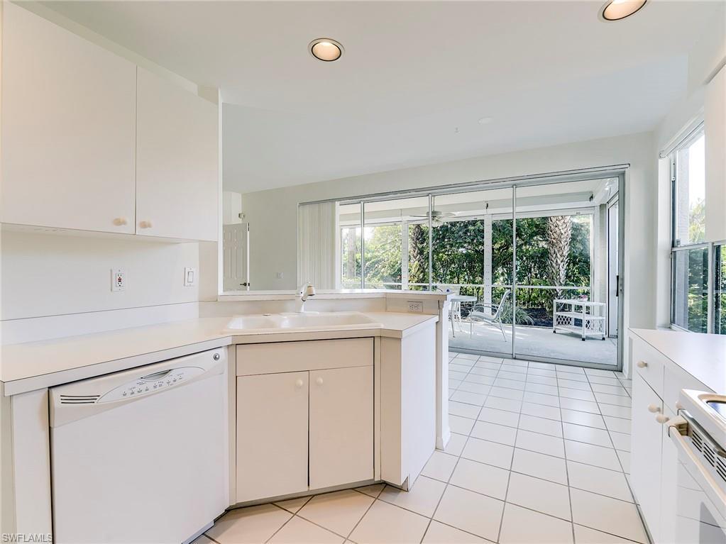 Image 4: Kitchen with white appliances, white cabinetry, a peninsula, light countertops, and light tile patterned flooring
