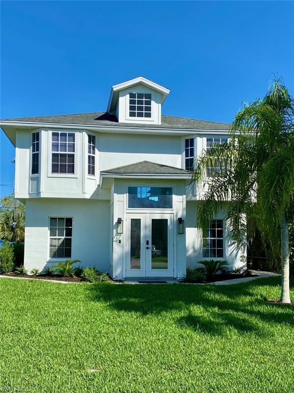 Image 1: View of front facade featuring a front yard, french doors, and stucco siding