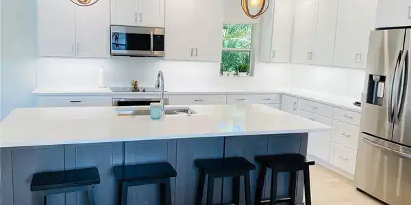Image 2: Kitchen with stainless steel appliances, white cabinets, pendant lighting, light wood-style floors, and a kitchen island with sink