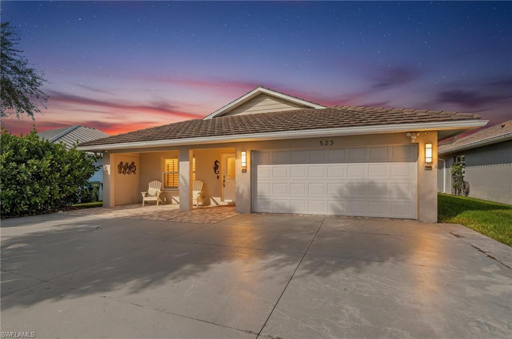 Image 1: View of front of home featuring stucco siding, concrete driveway, covered porch, and an attached garage
