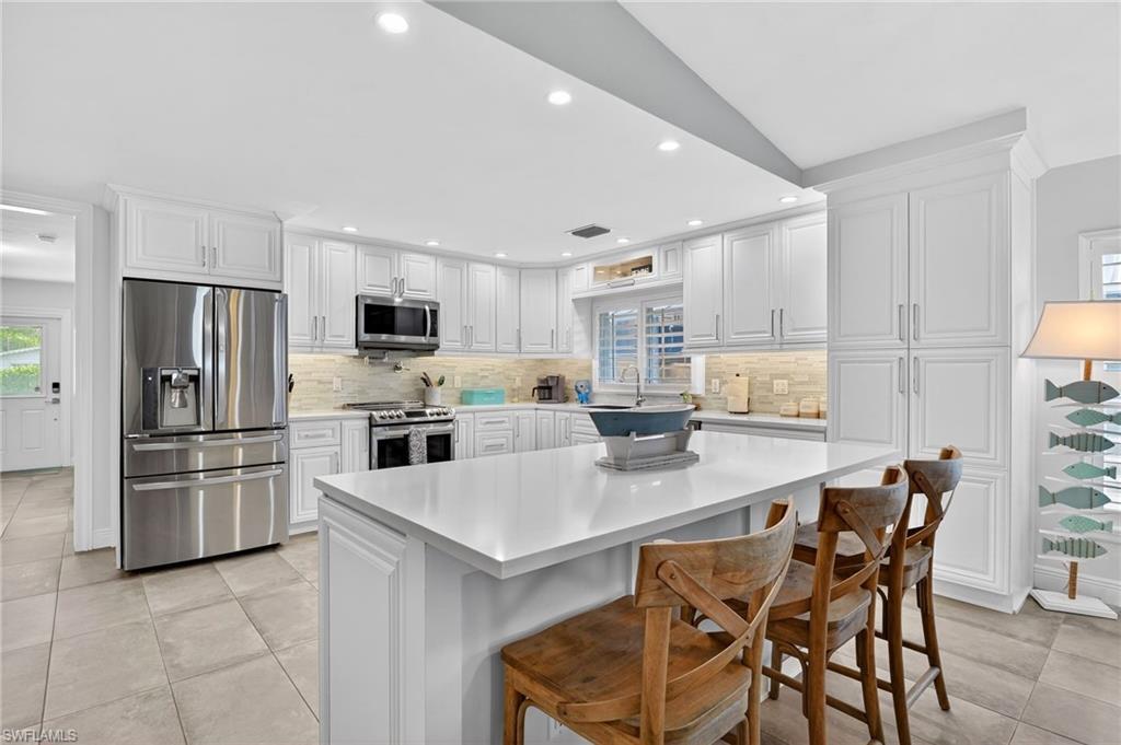 Image 3: Kitchen featuring appliances with stainless steel finishes, a breakfast bar area, white cabinetry, recessed lighting, and a kitchen island