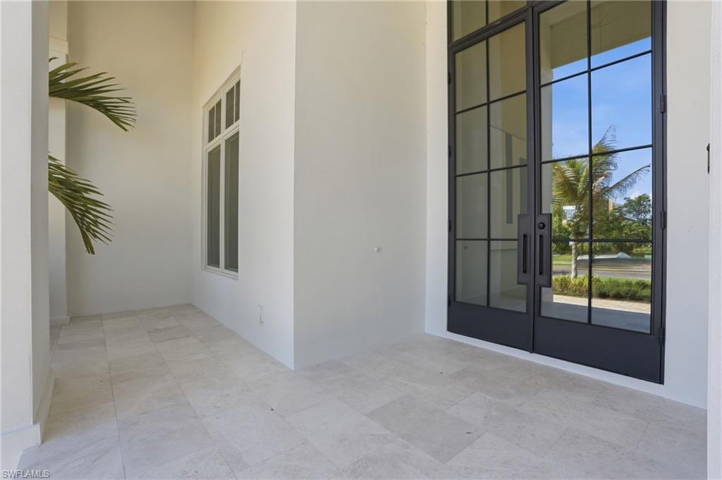 Image 3: The property features a tiled entry area with white walls and a large window, complemented by modern black framed glass entry doors