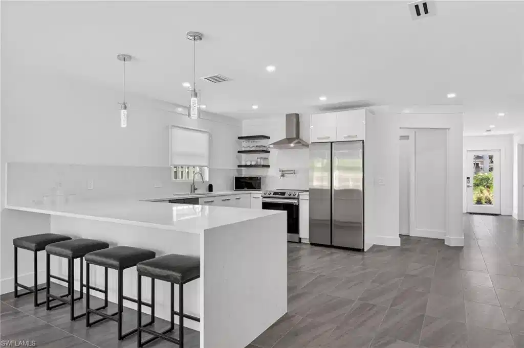 Image 1: Kitchen featuring a kitchen breakfast bar, open shelves, stainless steel appliances, white cabinetry, and hanging light fixtures